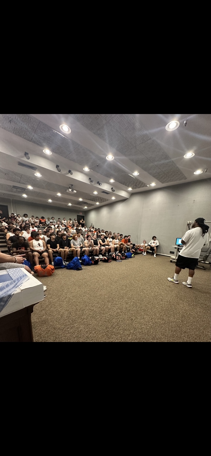 Alex Green speaking to a room of athletes