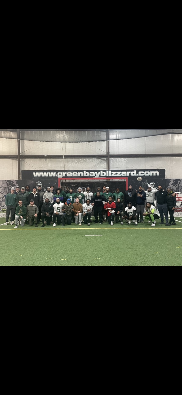Alex Green with a football team on an indoor field