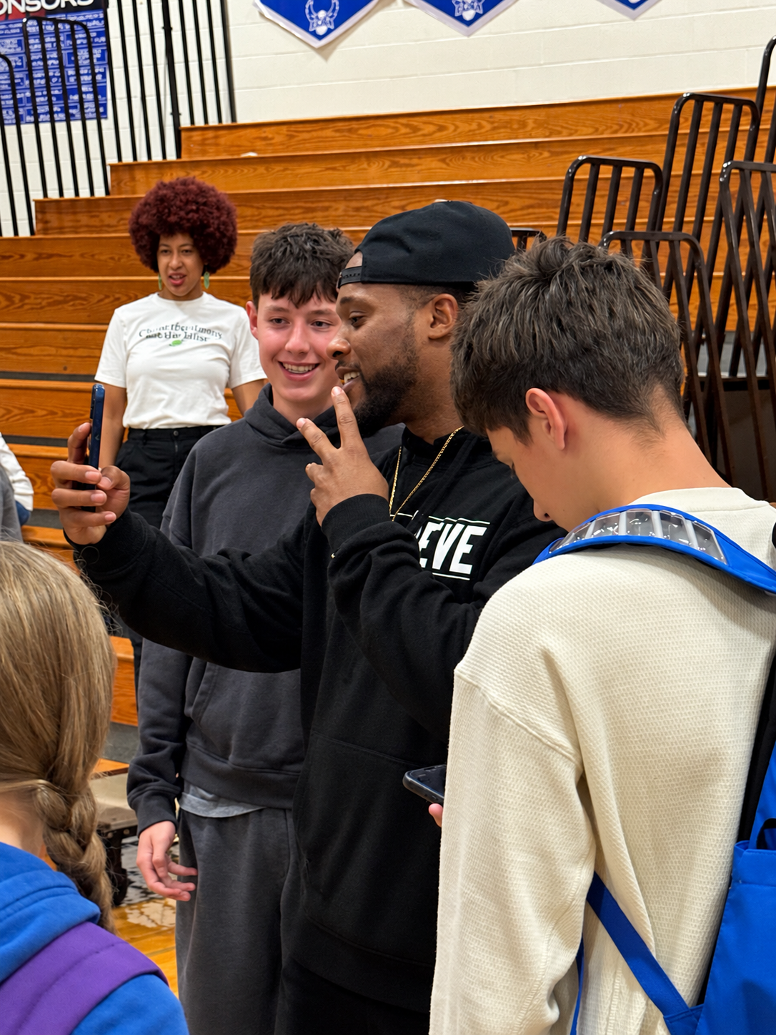 Alex Green taking a photo with students after an assembly