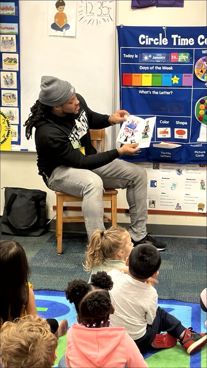 Alex Green reading his book to young children in a classroom