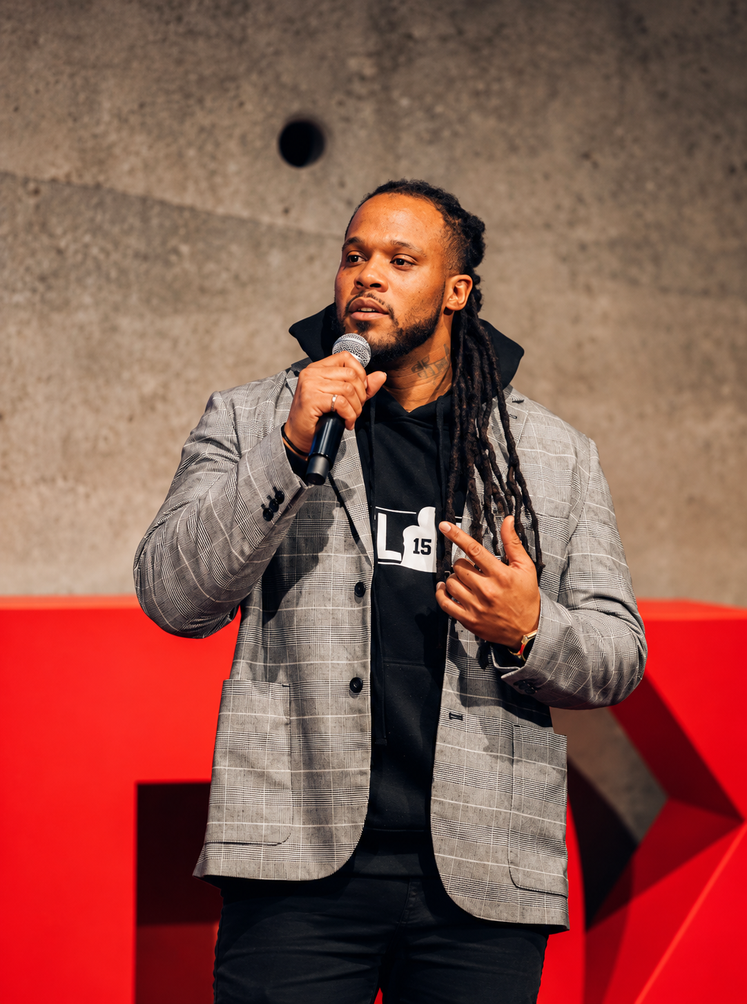Alex Green speaking onstage with a microphone