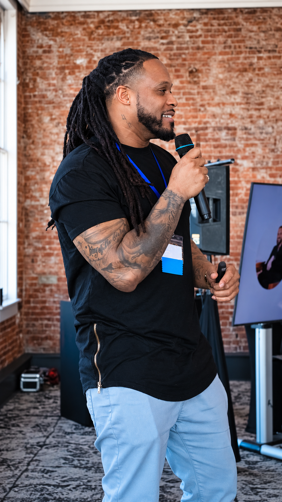Alex Green speaking with a microphone at an indoor event